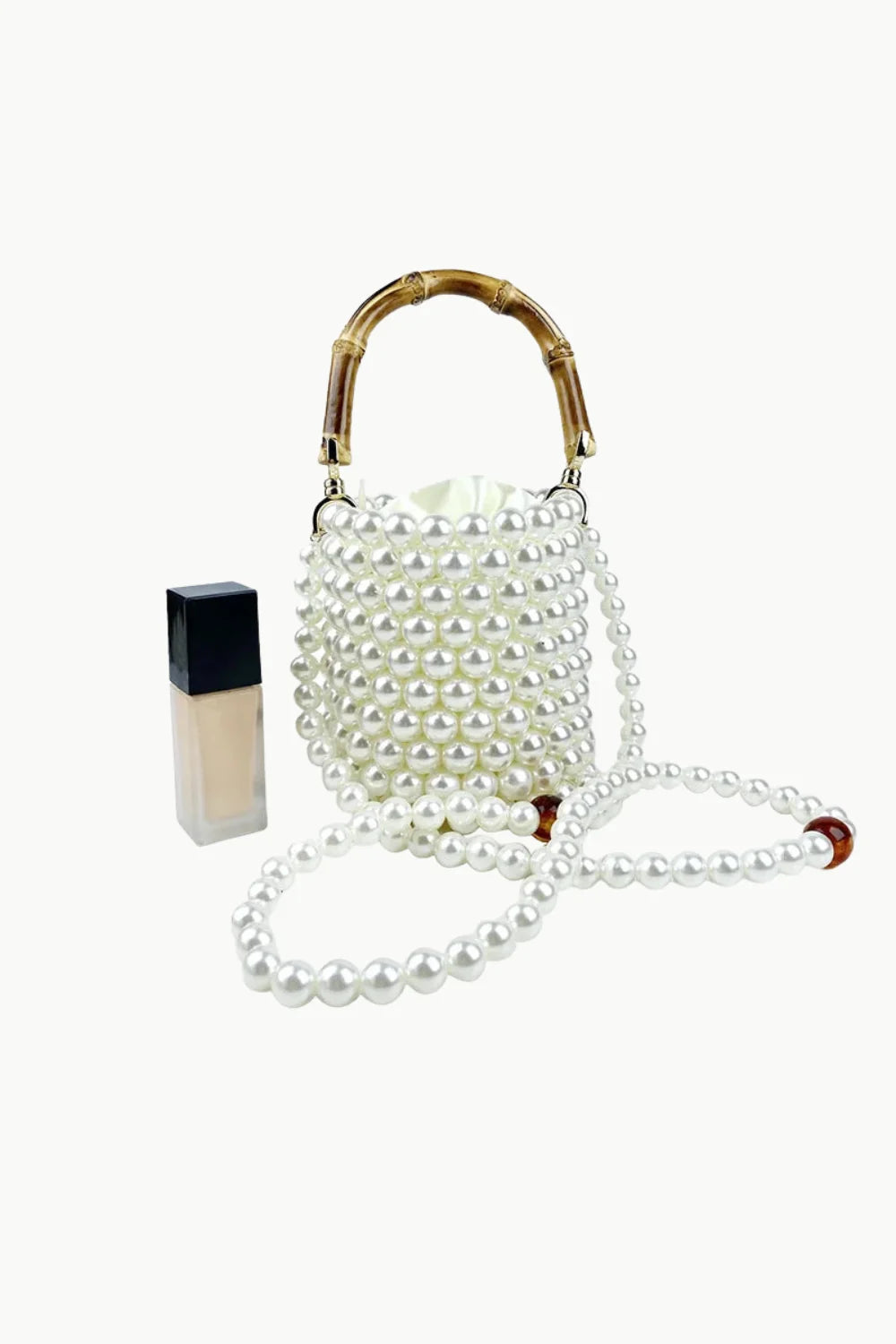 White pearl bucket bag with bamboo top handle and long pearl strap for stylish carry