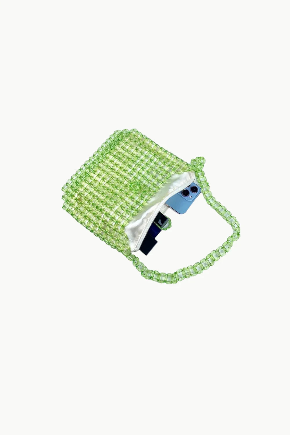 Light green beaded shoulder bag with white lining and blue-cased phone inside