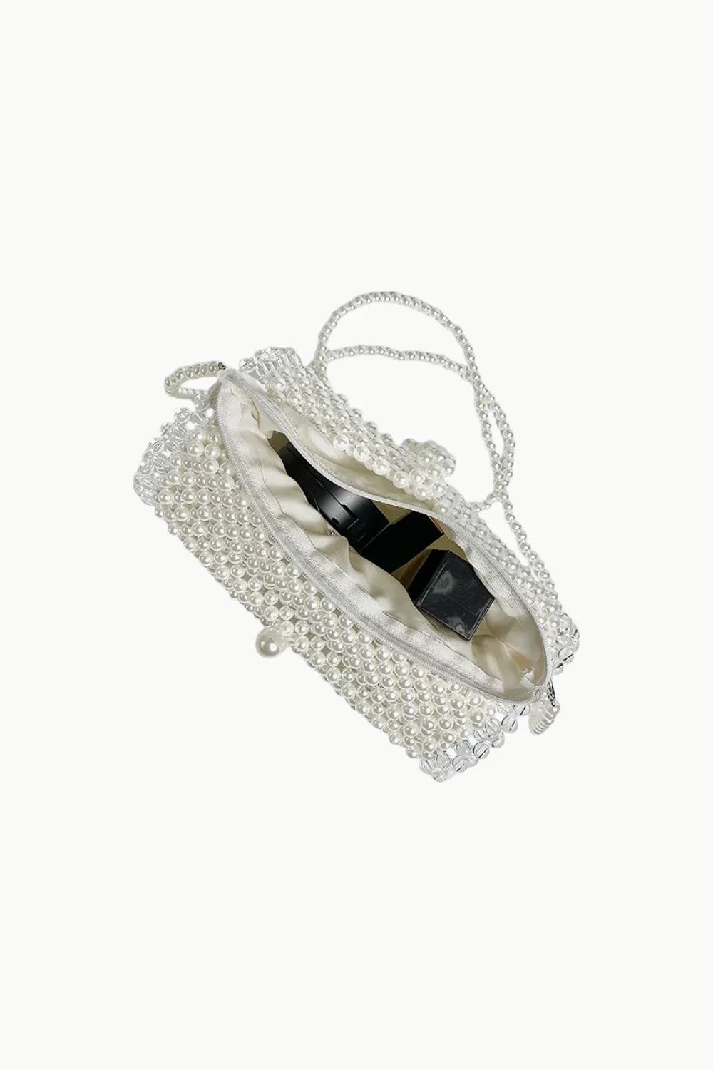 White beaded pearl bag with chain and pearl clasp holding two small dark bottles