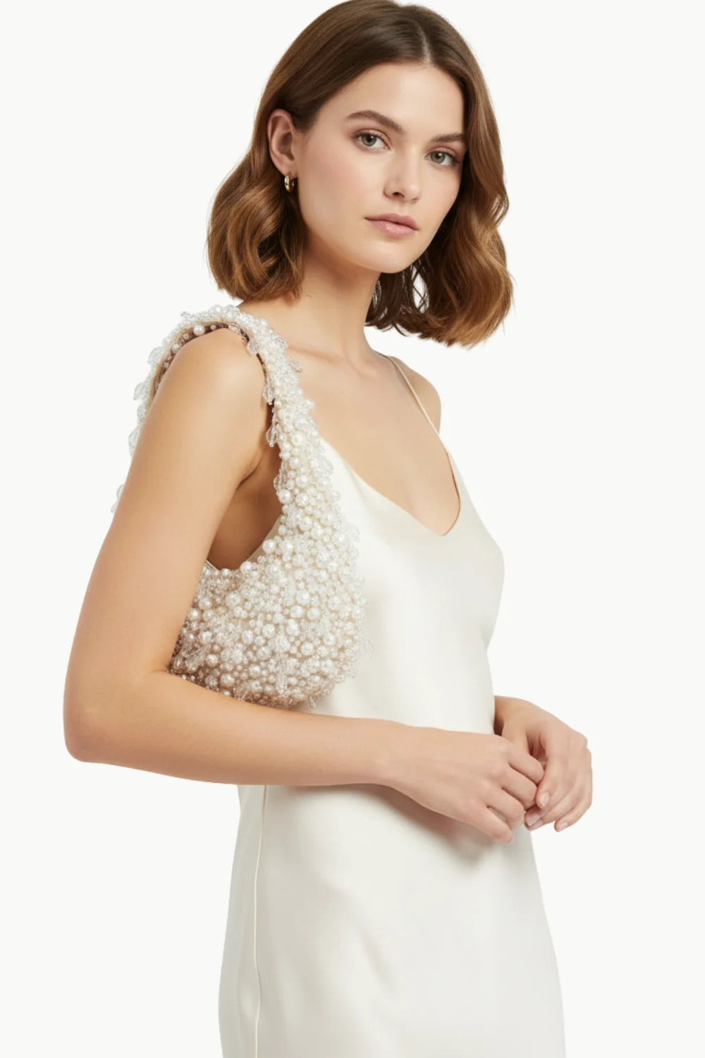 Woman holding a cream slip dress and beaded shoulder bag with Pearl Bag Charm