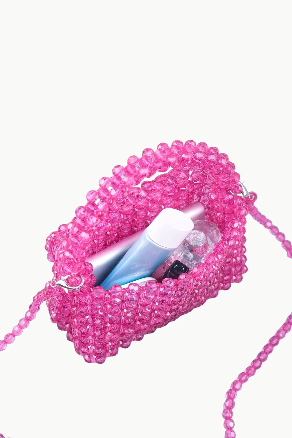 Pink beaded bag charm with small cosmetics and light blue lip balm inside