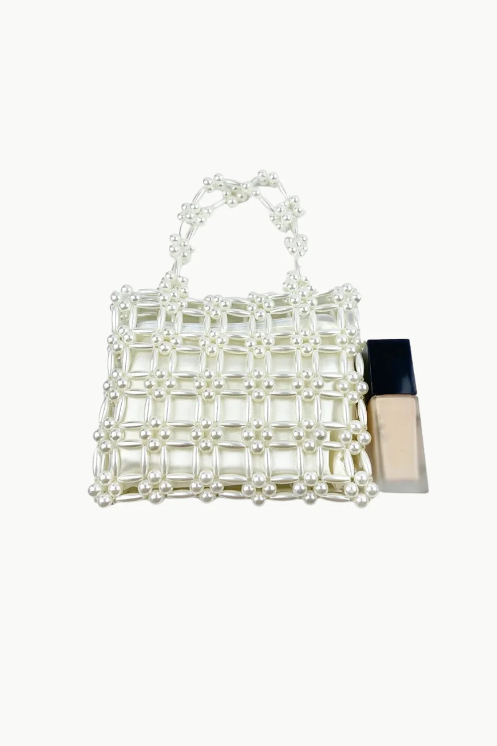 White pearl beaded bag with top handle next to liquid foundation, Square Beaded Bag style