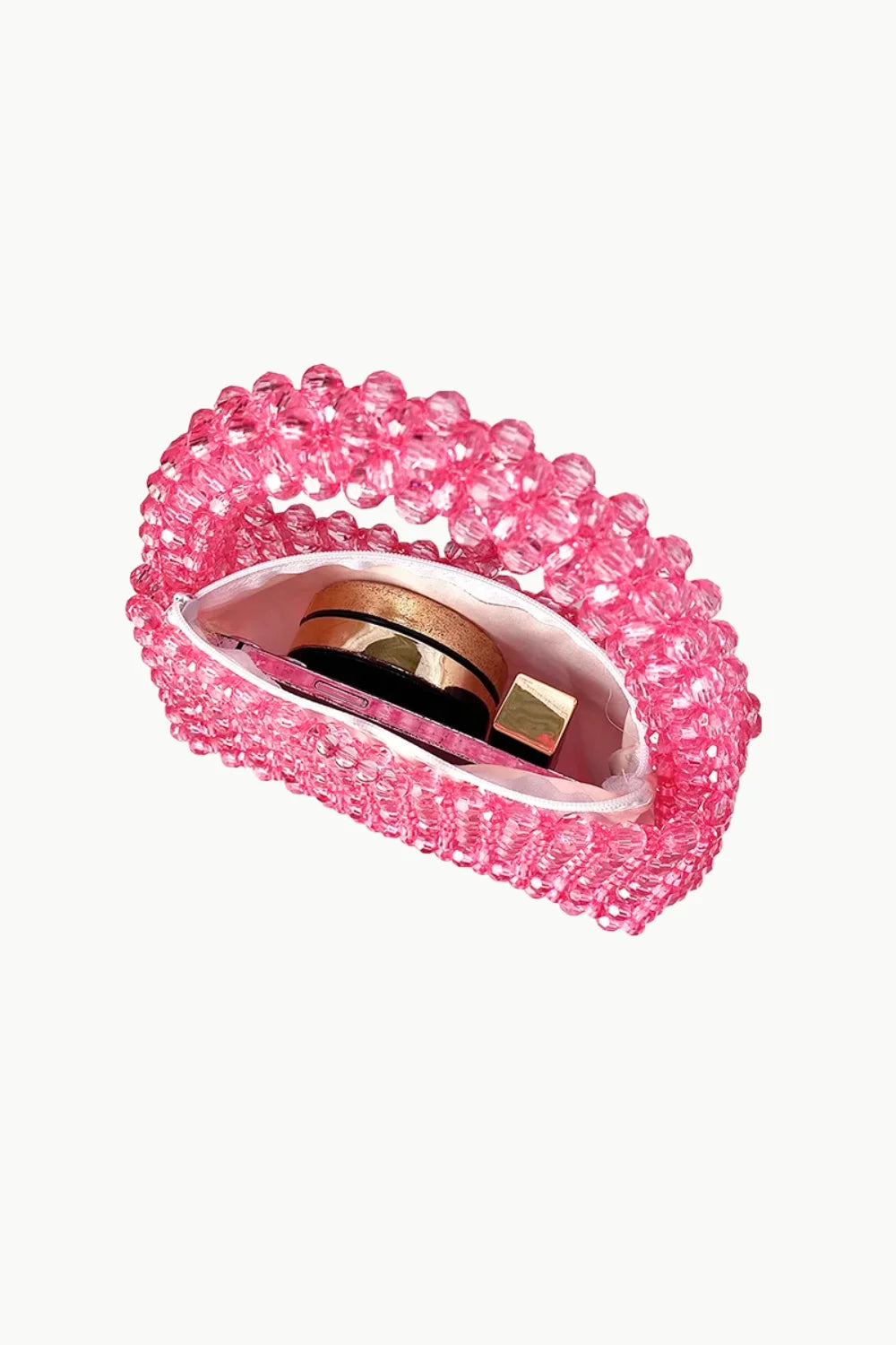 Pink beaded handbag with cosmetic items inside, displayed with a white beaded purse