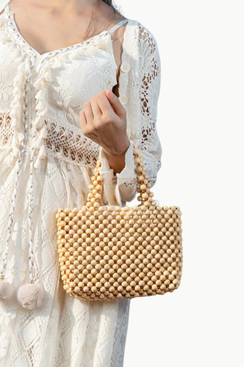 Woman holding a 70s wooden beaded bag in a white lace dress for stylish vintage look