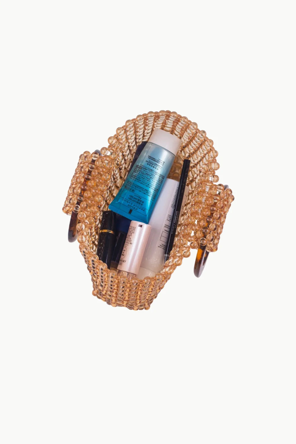 Gold beaded handle bag filled with beauty products, stylish beaded handle bag accessory