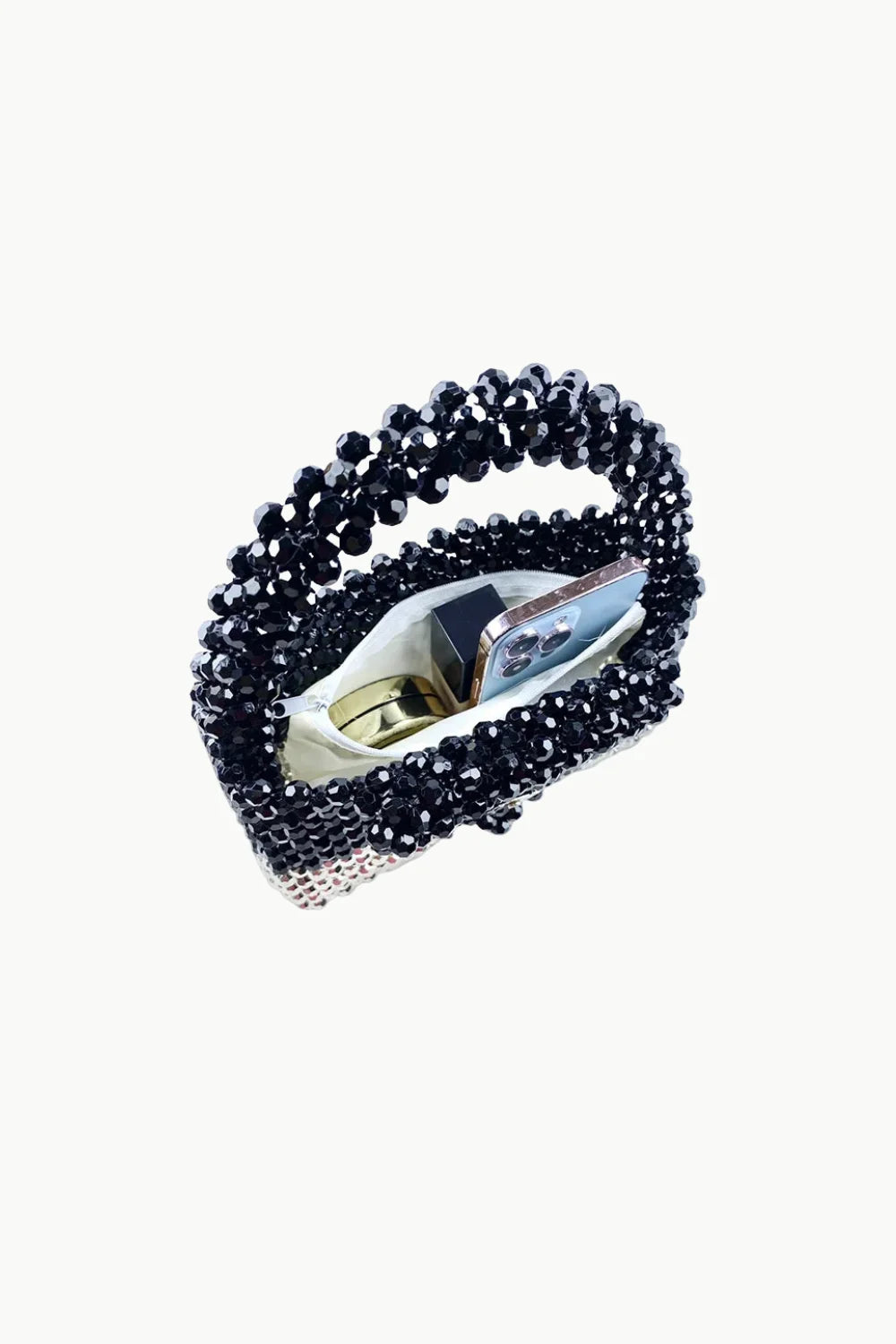 Black beaded bag with white lining holding smartphone and golden compact, silver beaded bag style