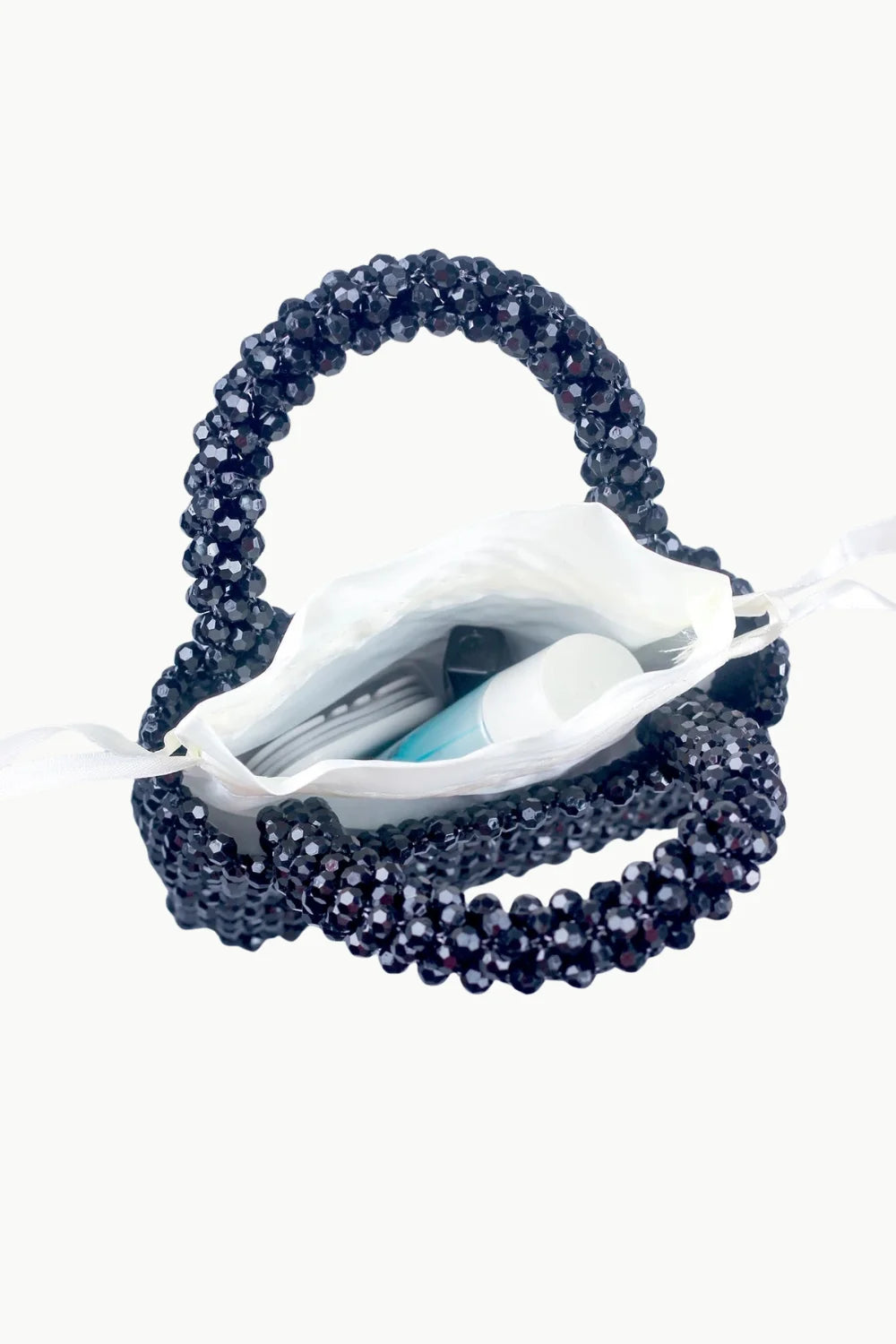 Black beaded handbag with white fabric lining and drawstring closure holding personal items