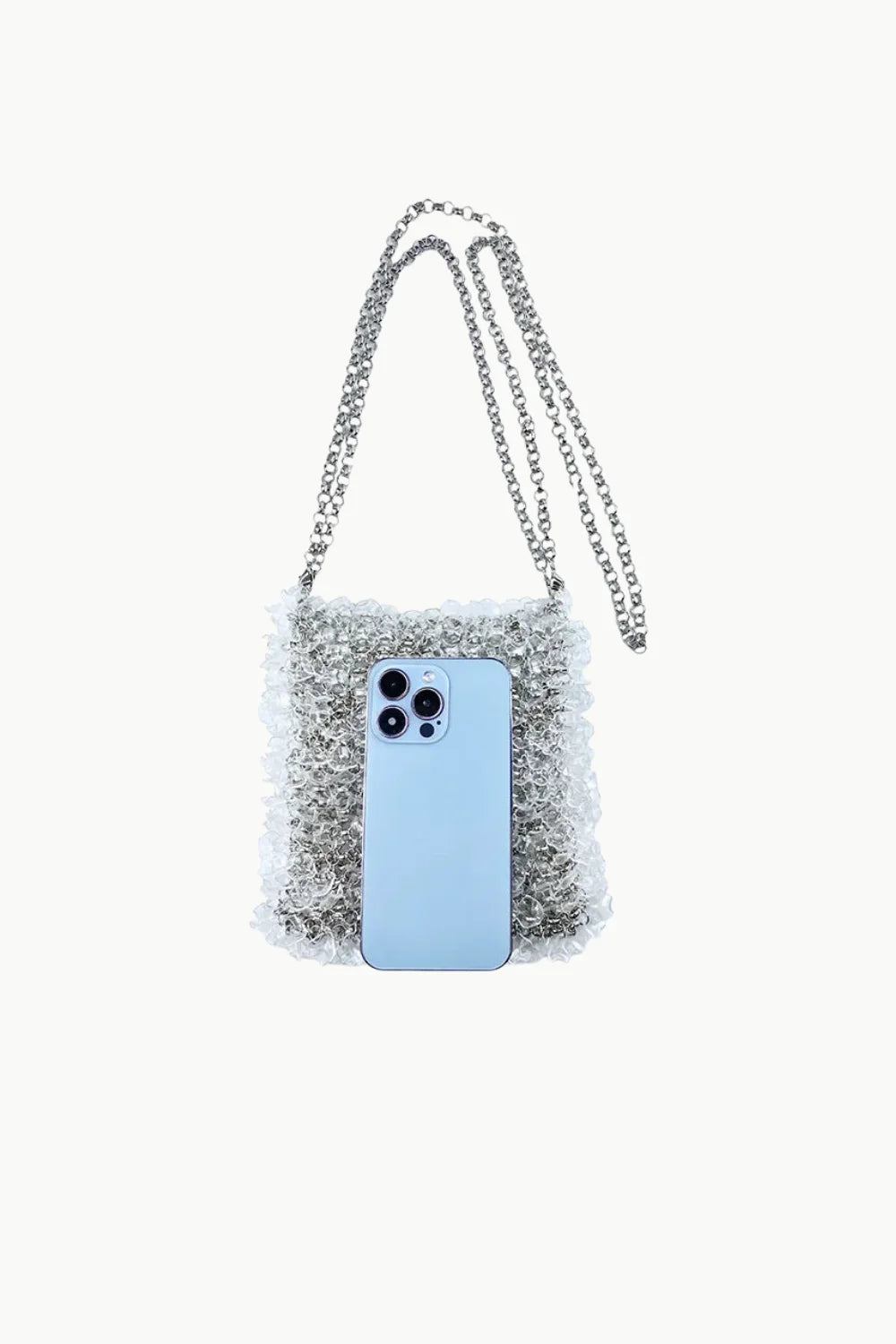 Silver-toned crystal-embellished beaded crossbody bag with chain strap and light blue smartphone for scale