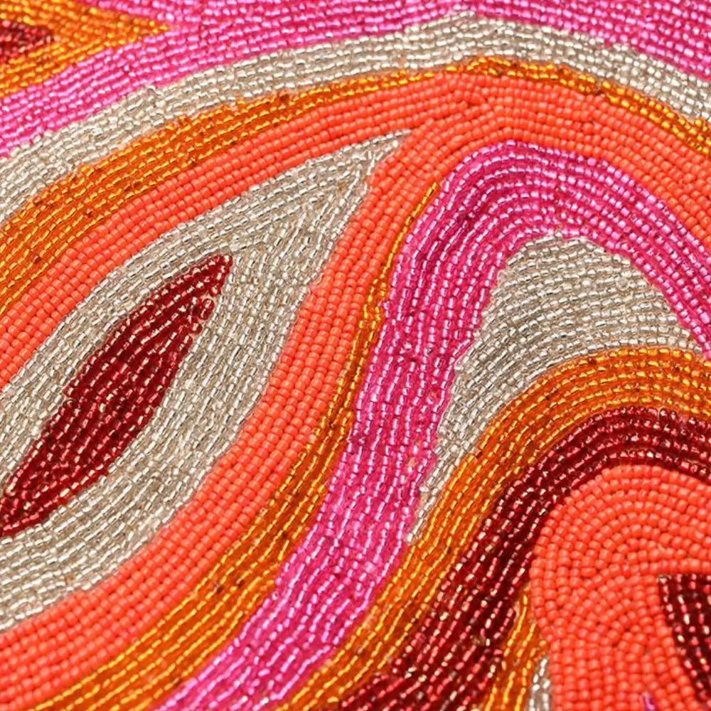 Handcrafted beaded bag detail with pink, orange, red, and gold swirl bead embroidery.