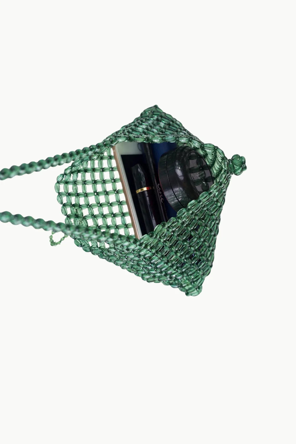 Green beaded shoulder bag holding a pen and small book, stylish beaded shoulder accessory