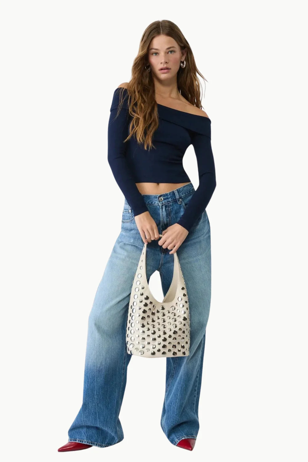 Woman modeling Leather Beaded Bucket Bag with off-the-shoulder navy crop top and wide-leg jeans