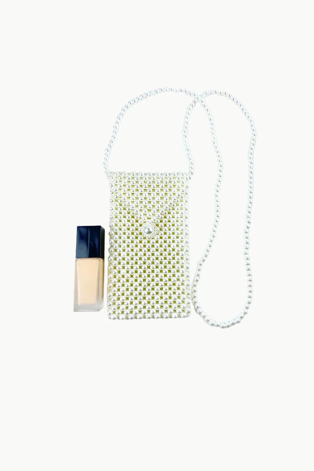 Pearl Crossbody Bag with beaded design and pearl strap next to liquid foundation
