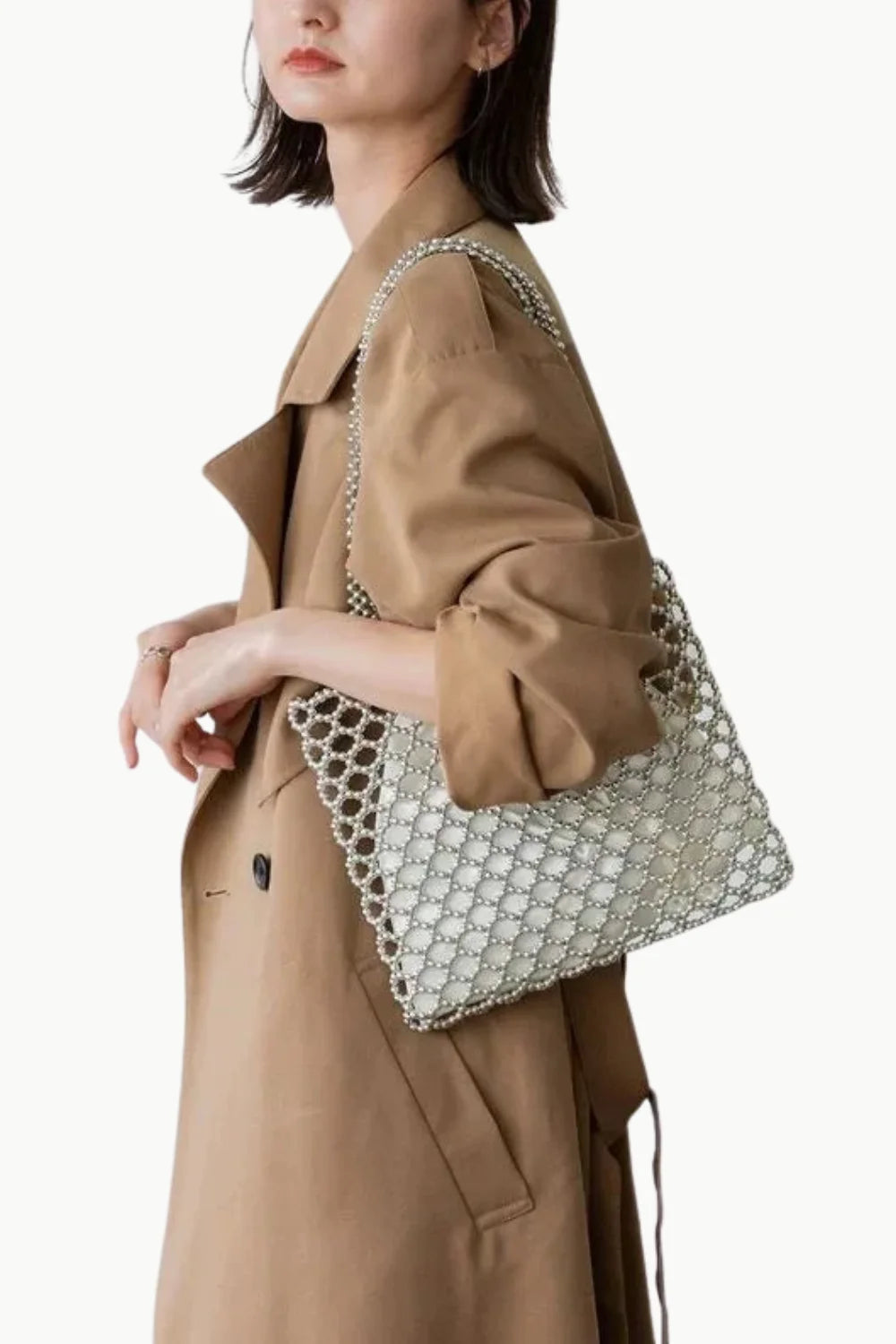 Fashionable woman in tan trench coat carrying a stylish Pearl Tote Bag with beaded mesh design