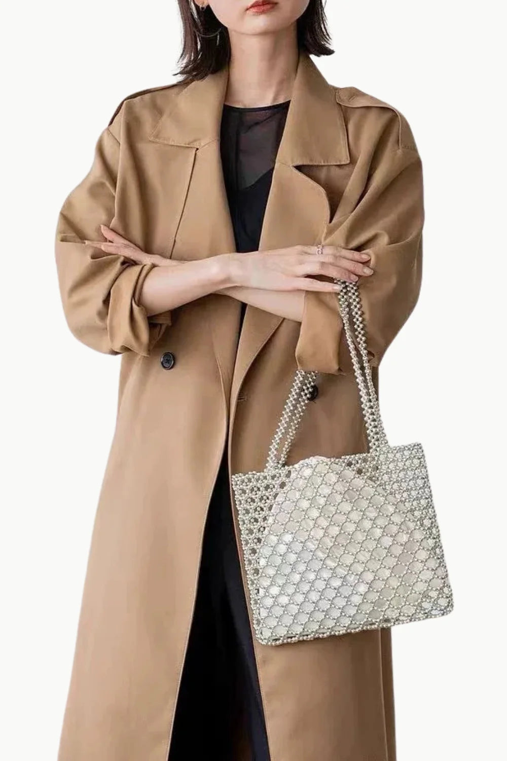 Woman in tan trench coat holding Pearl Tote Bag with clear beaded design