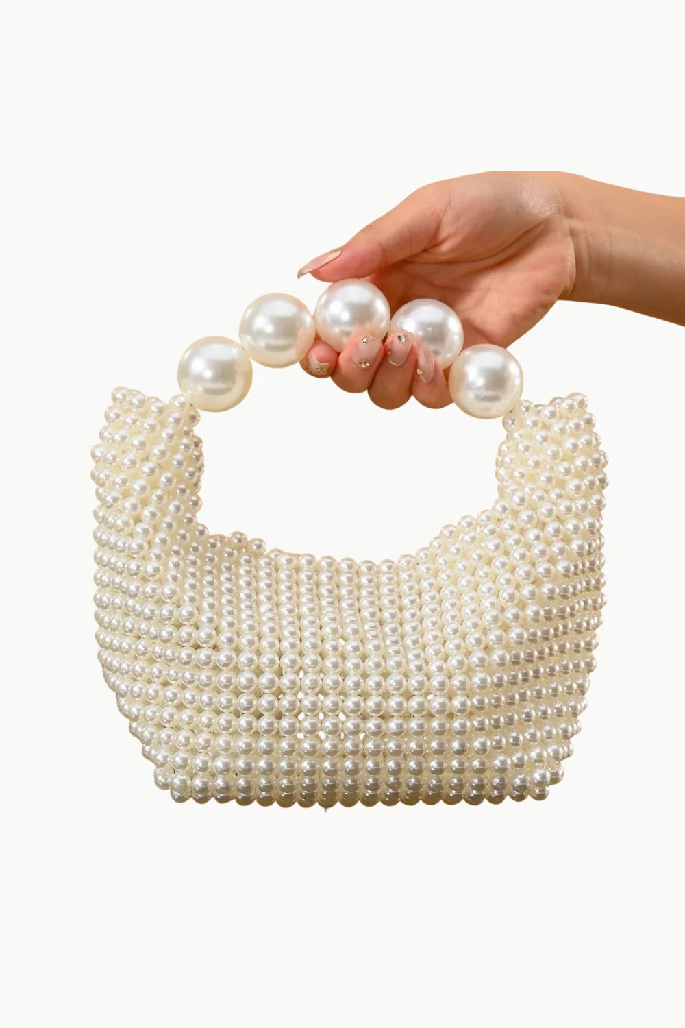 Woman’s hand holding a pearled ivory bag with large pearl handles showcasing elegance