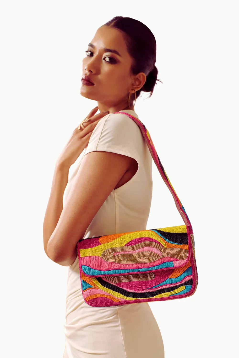 Woman modeling a pink beaded handbag with a colorful wavy design