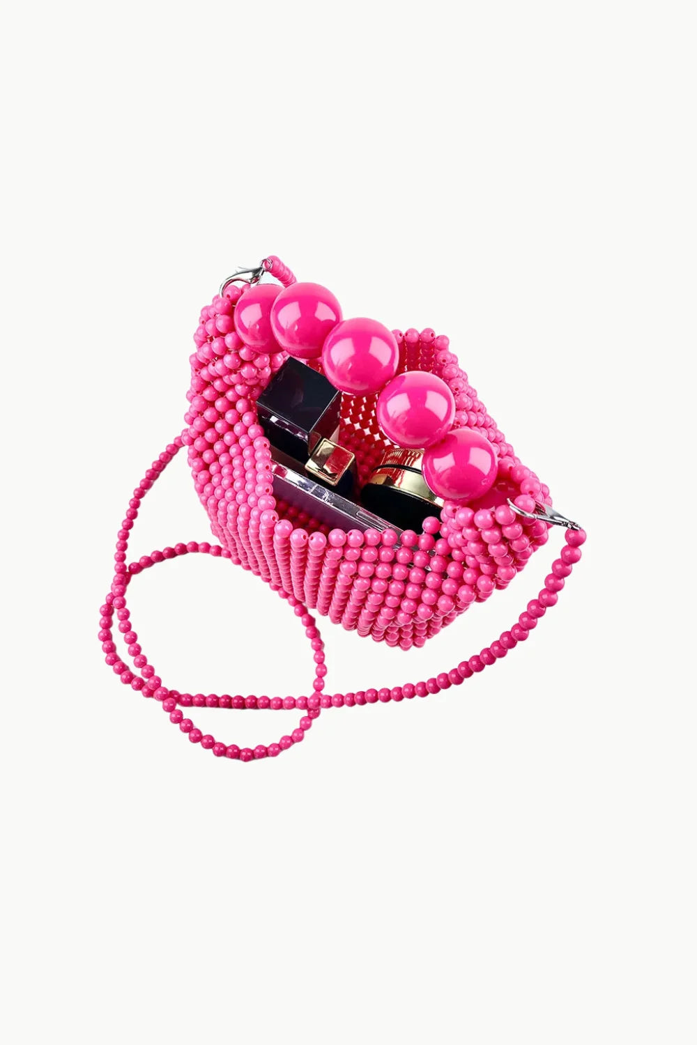 Pink beaded shoulder bag with spherical handles and cosmetic items inside