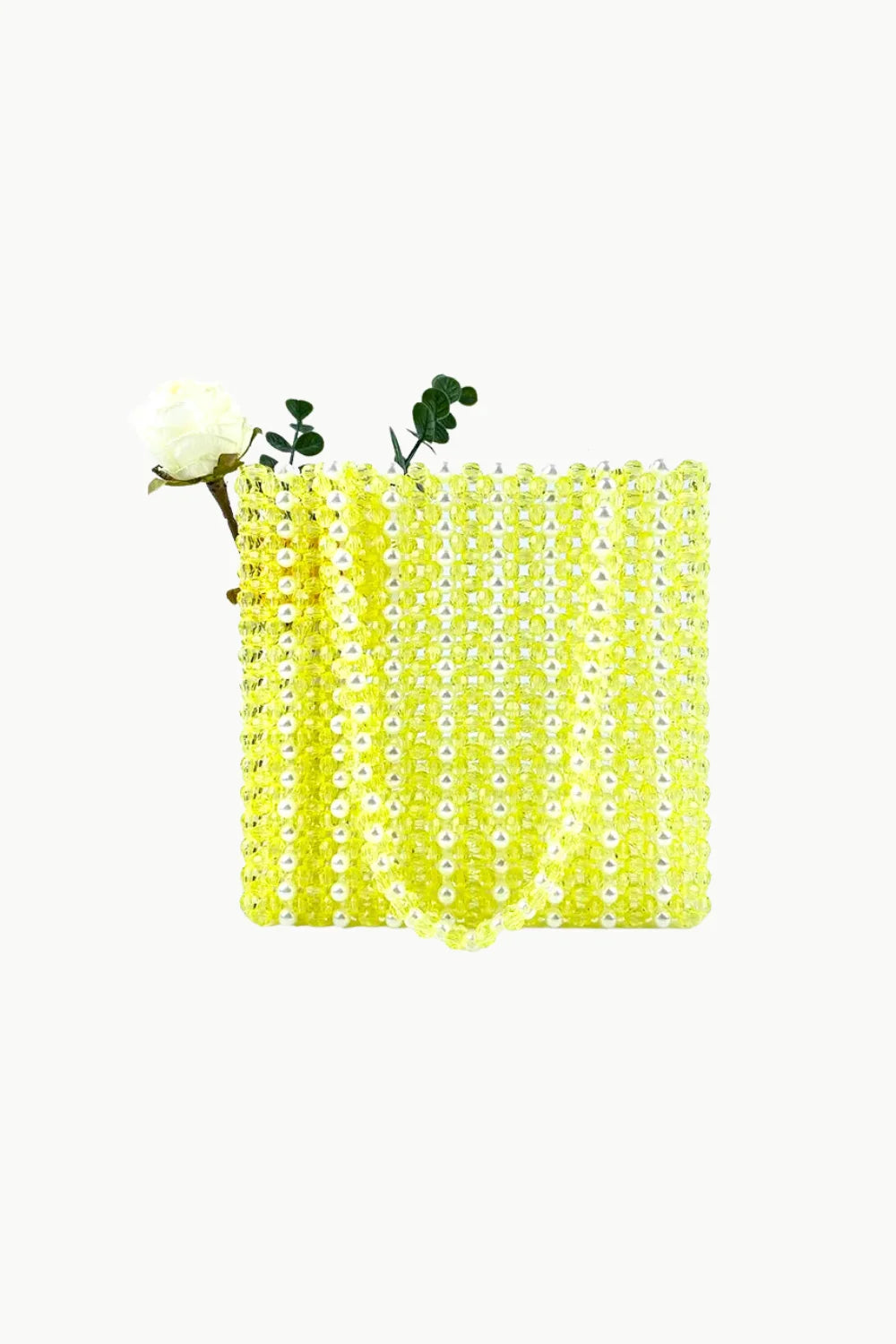 Bright yellow Sol Mer beaded bag with white flower and green foliage peeking out