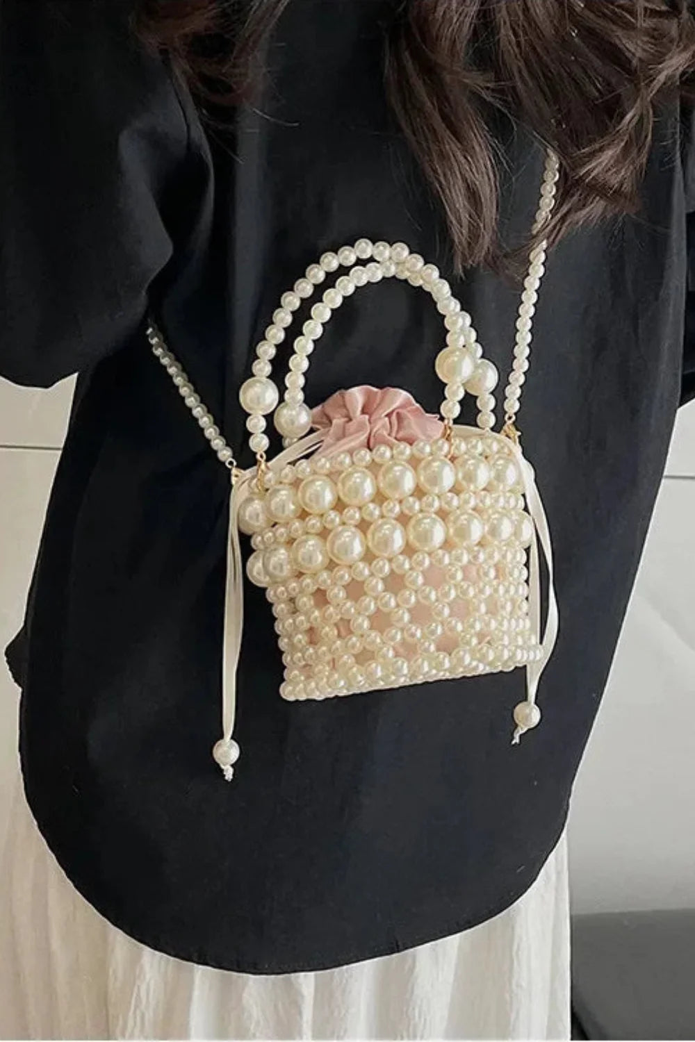 Pearl-beaded bucket bag with pink drawstring pouch and pearl top handles for trendy bead bucket style