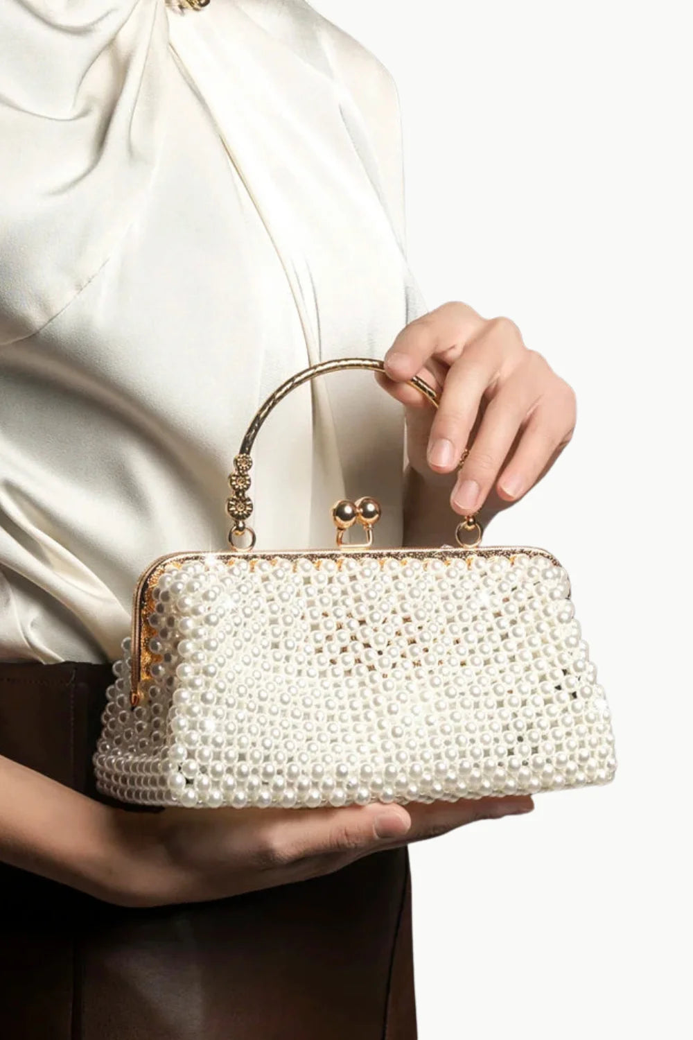 Vintage pearl beaded clutch with gold-tone frame held by a woman for elegant style