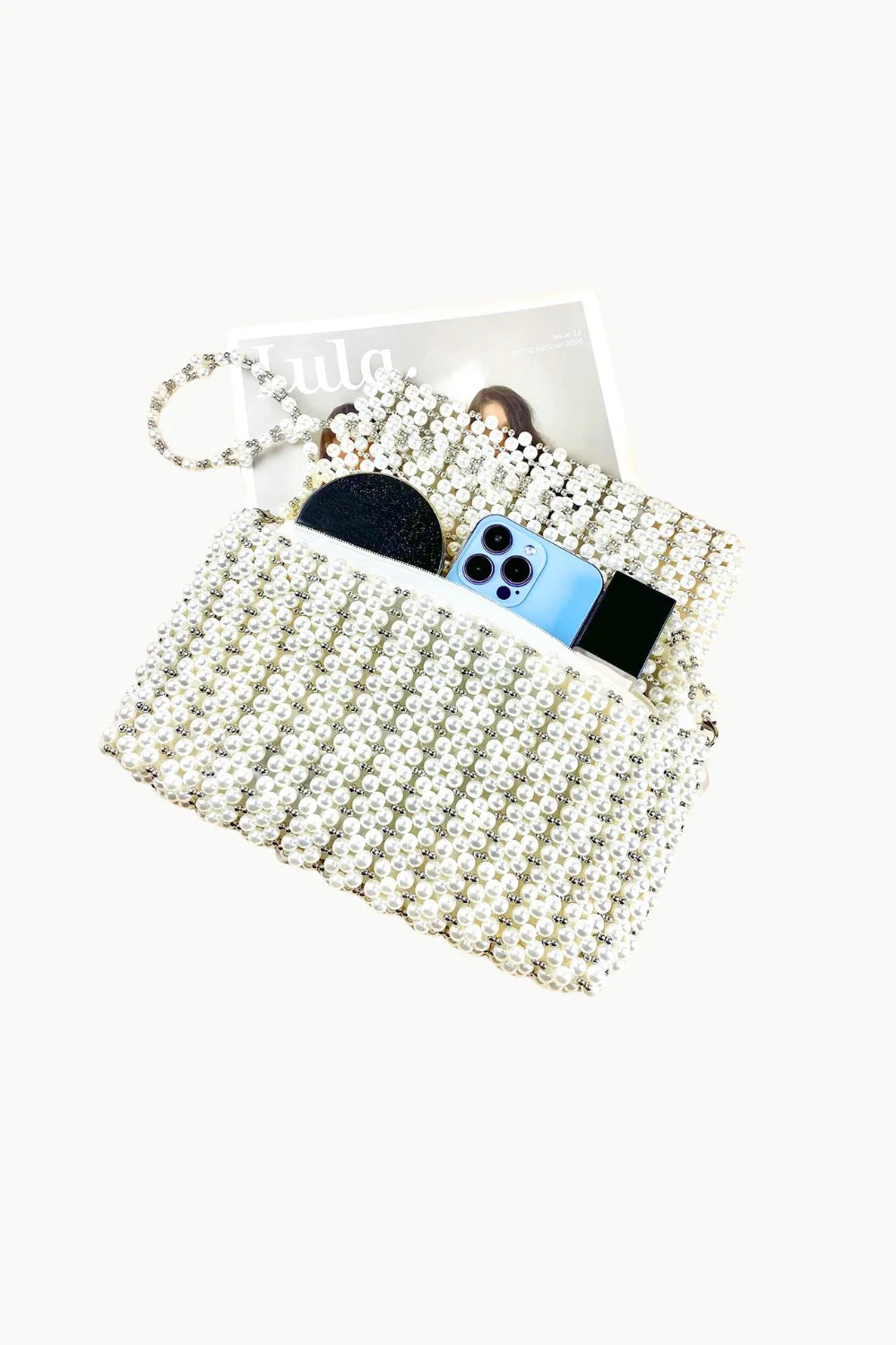 White beaded evening bag with zipper closure, wrist strap, holding smartphone and compact