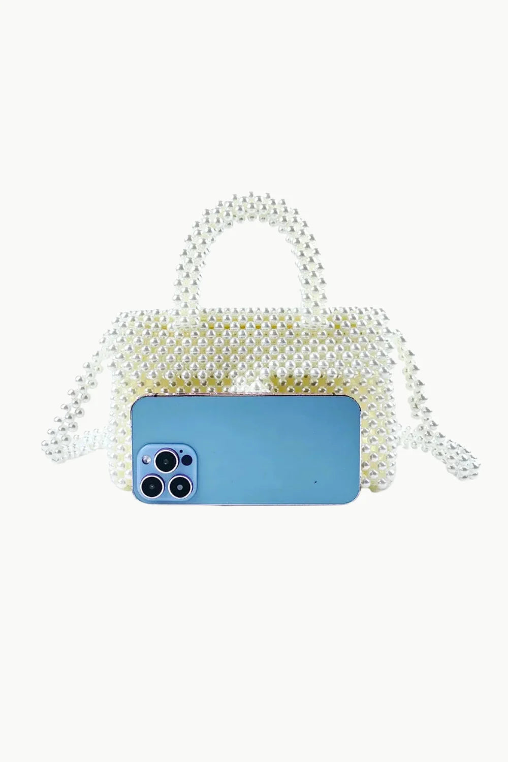 White beaded handbag with top handle and shoulder strap holding a light blue smartphone