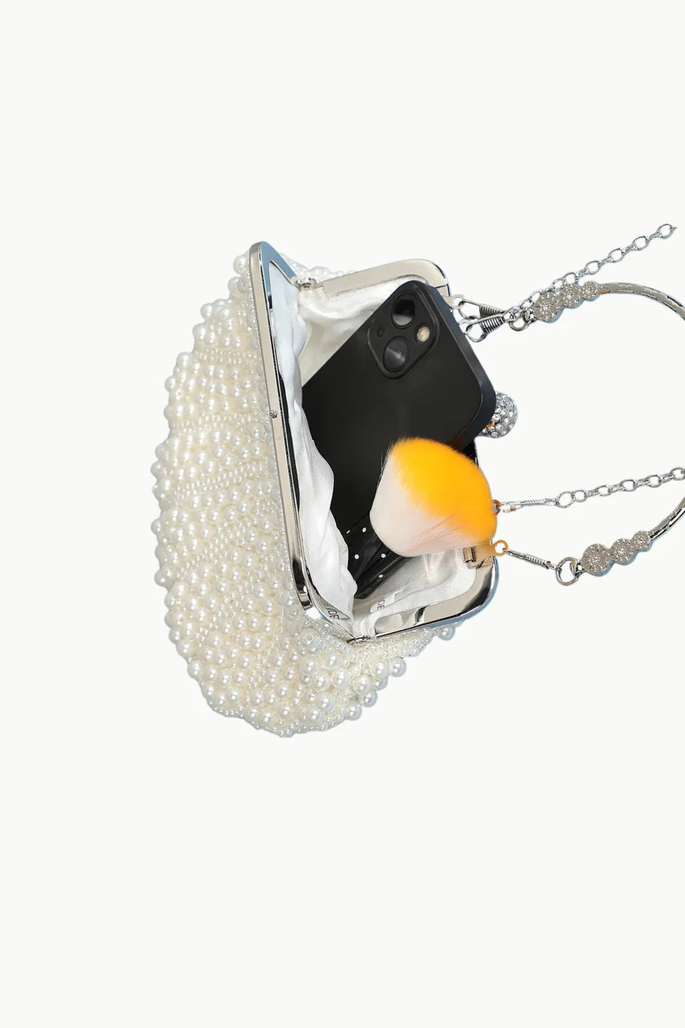 White pearl clutch bag with phone and two-toned accessory inside showcasing elegance